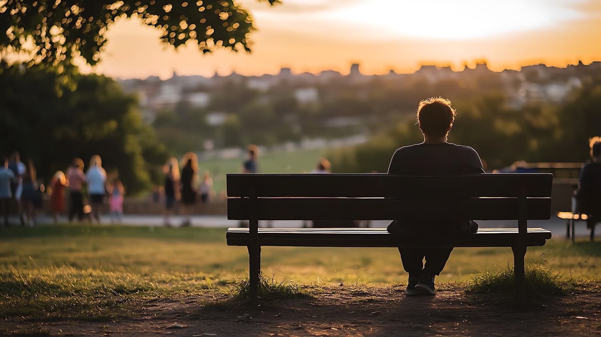 A man sits on a park bench, looking out at the city skyline. The scene is peaceful and serene, with the man alone on the bench, taking in the view